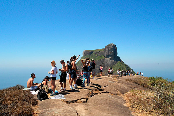 Imagem de pessoas na Pedra Bonita, no Rio de Janeiro, após fazer a trilha da Pedra Bonita, que dá vista para a Pedra da Gávea ao fundo.